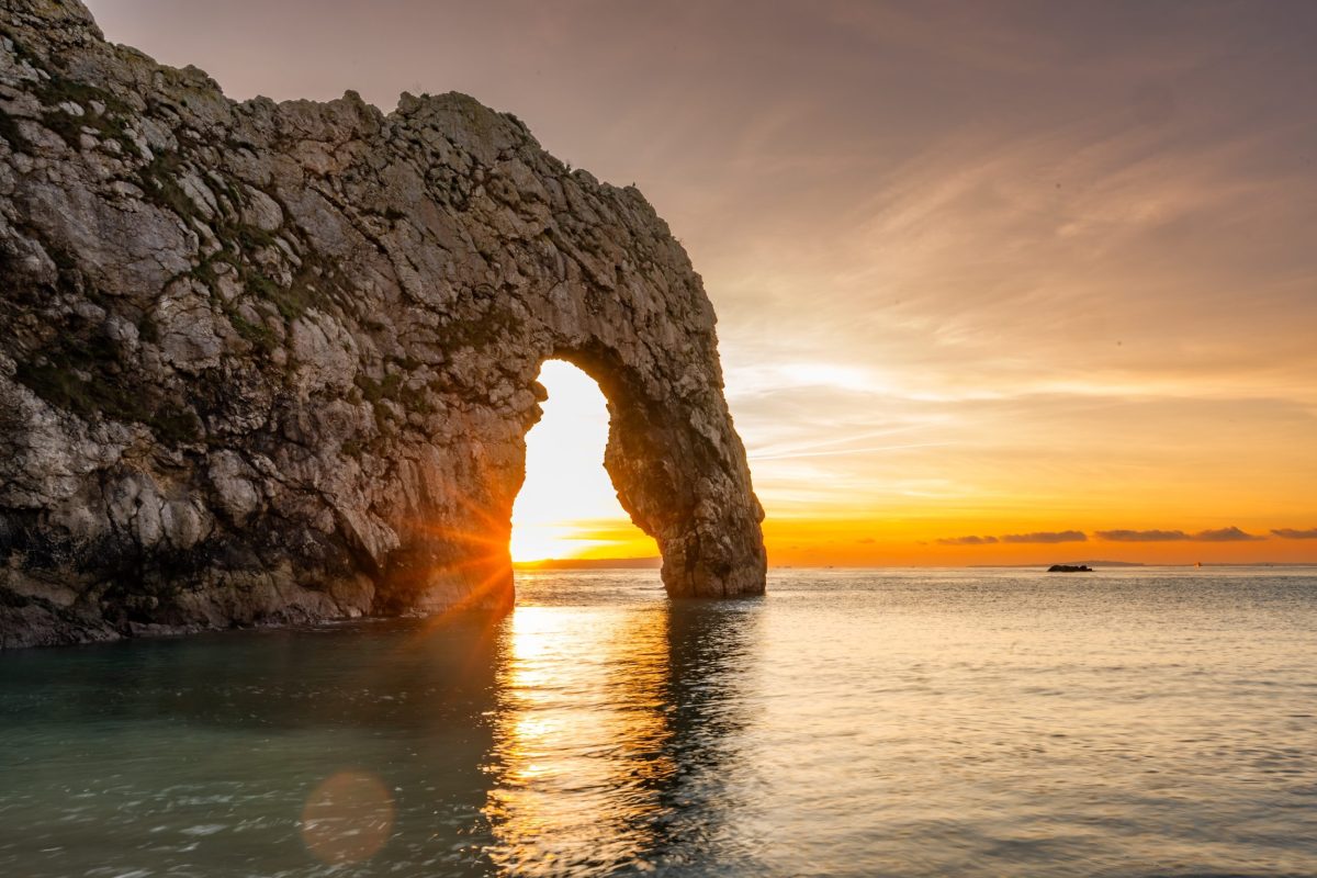 Sunrise behind the limestone arch at Durdle Door on Dorset's Jurassic Coast.