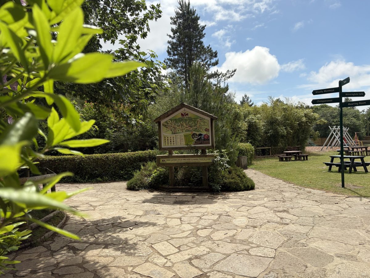 Entrance to Monkey World Ape Rescue Centre in Dorset with tropical planting and attraction signposts