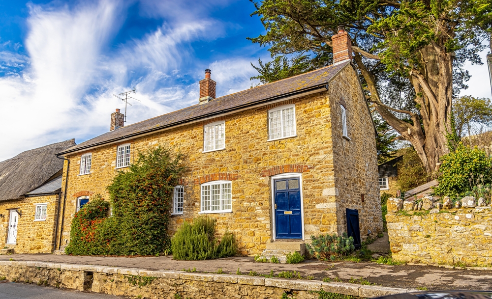 Traditional honey-coloured stone cottages with blue doors in the historic village of Abbotsbury, Dorset