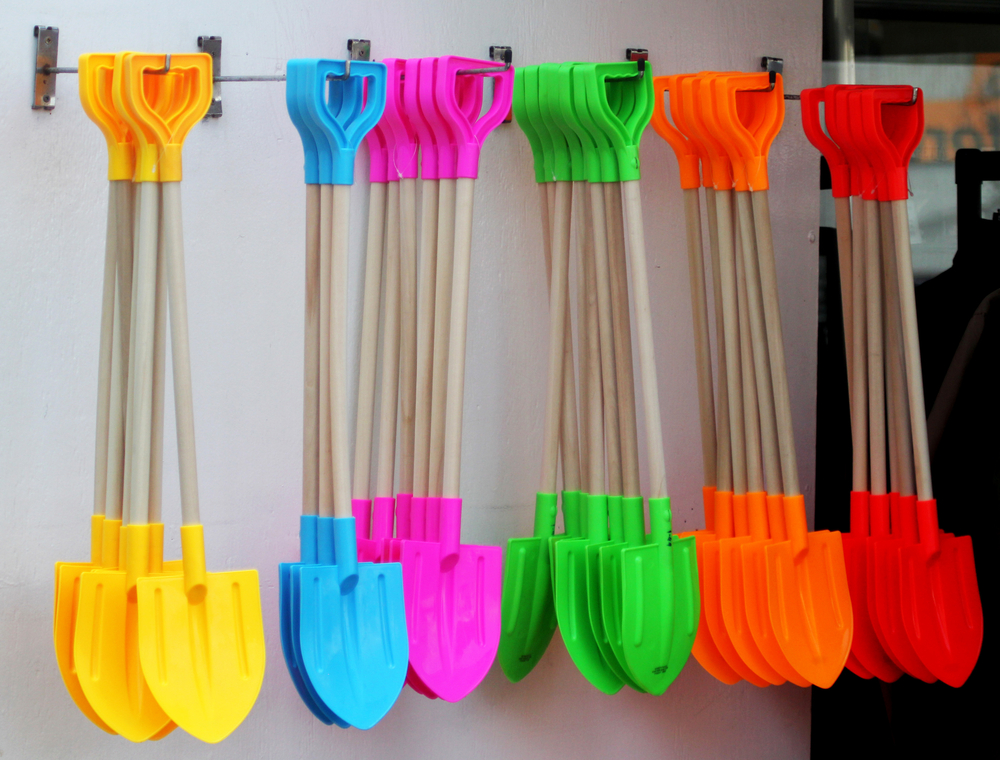 Colourful beach spades hanging outside a traditional seaside shop.