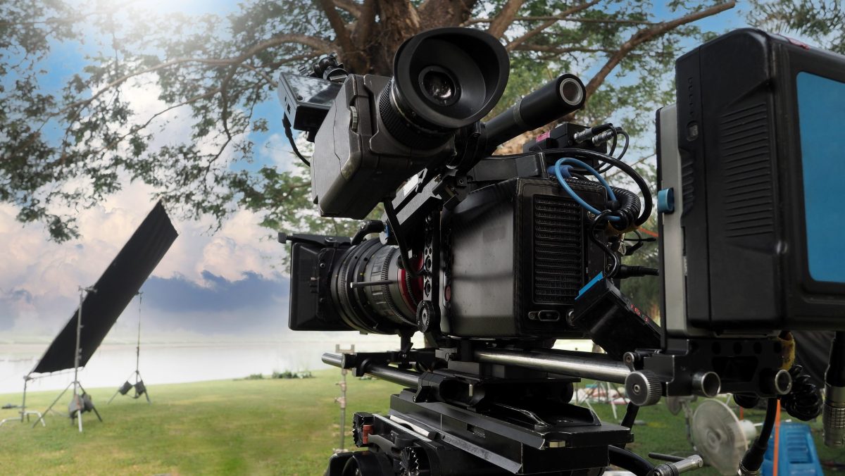 Professional film production camera with monitor and lighting equipment set up on location.