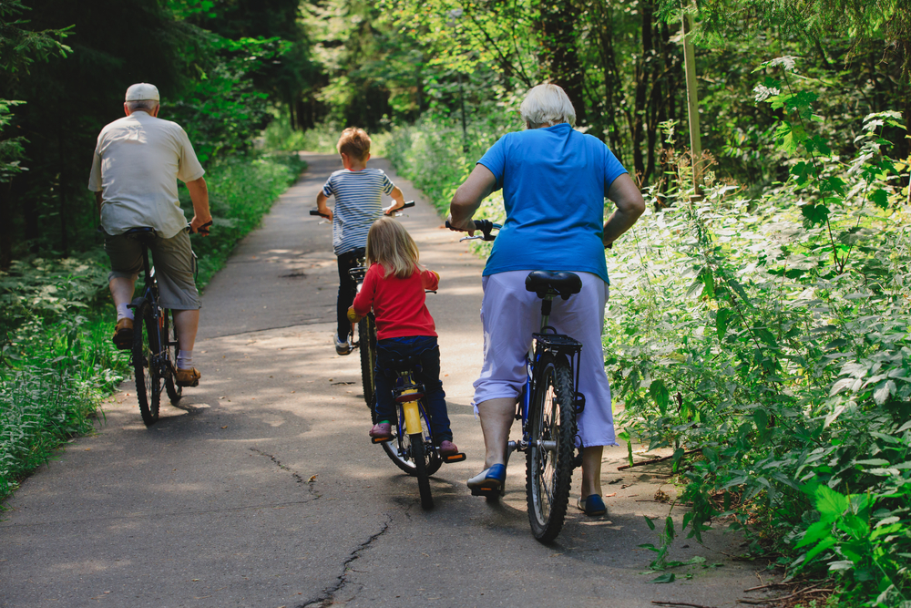 Grandparents cycling with their grandchildren along a countryside trail.