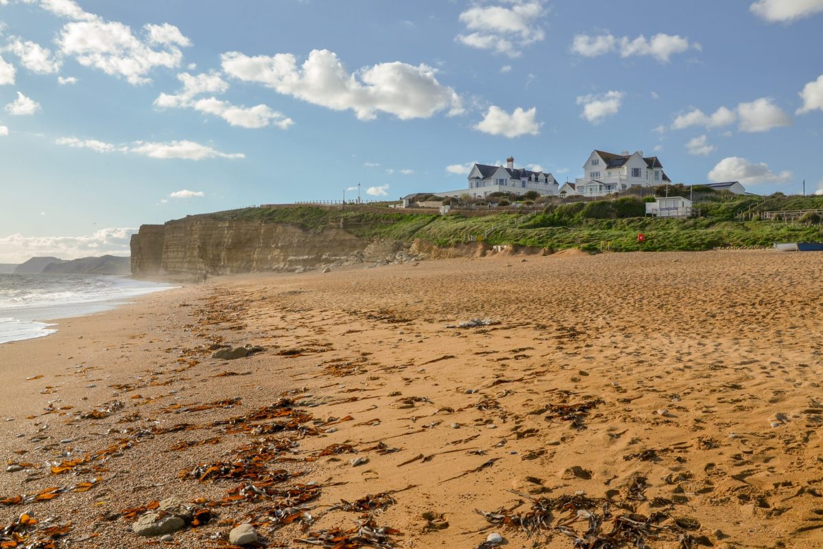 Empty sandy Hive Beach in Burton Bradstock, under blue skies