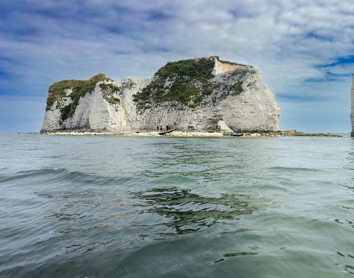 Kayaks on the sea below Old Harry Rocks with the white chalk cliffs of Studland in Dorset.
