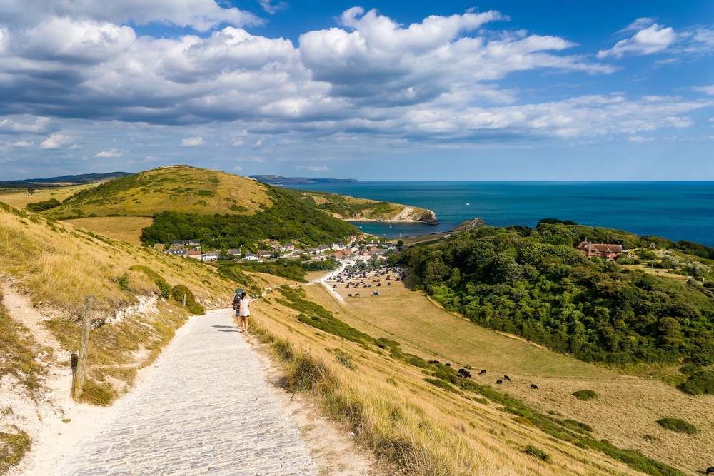 Stone steps leading down to Lulworth Cove with the Purbeck Hills and coastline beyond in Dorset.