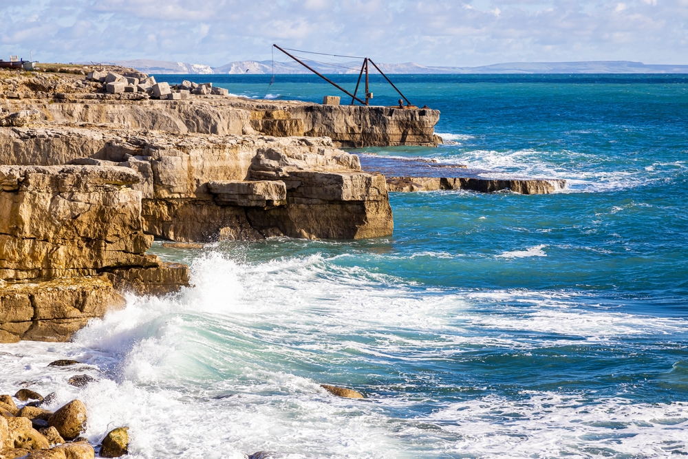 Rugged Portland stone coastline with crashing waves along the Jurassic Coast in Dorset.