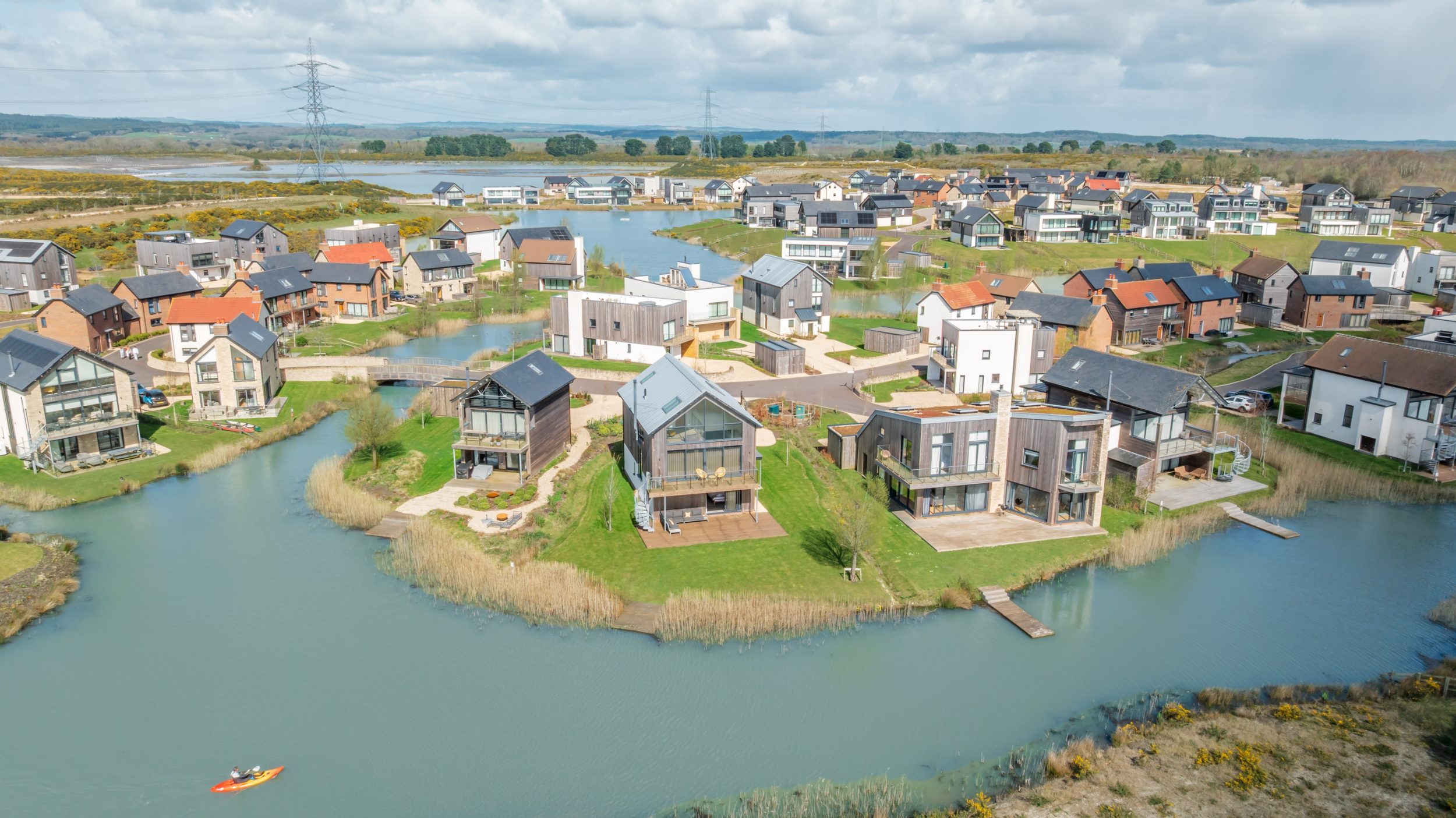 Aerial view of Silverlake Estate in Dorset with lakes, luxury holiday cottages and a kayaker on the water