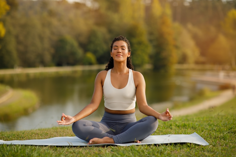 Guest enjoying a peaceful yoga session beside the lake at Silverlake Estate in Dorset.