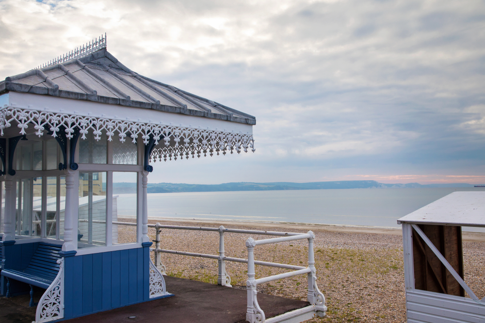 View of Weymouth Beach from the Esplanade with a Victorian beach shelter and calm sea in Dorset.