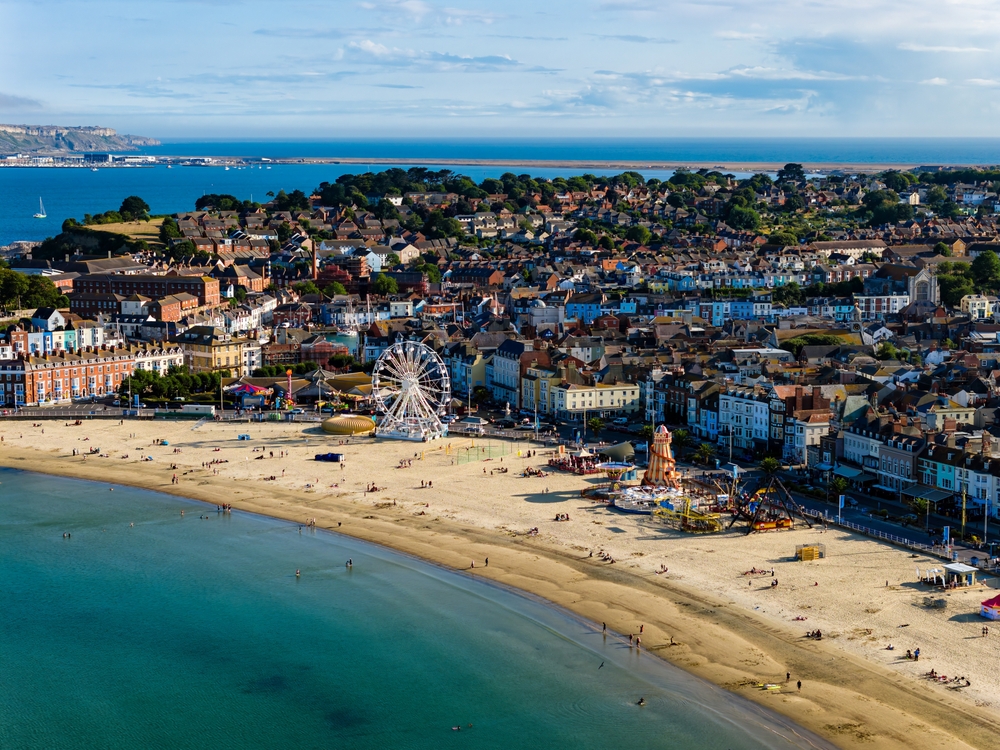 Observation wheel and traditional seaside amusements on Weymouth Beach.