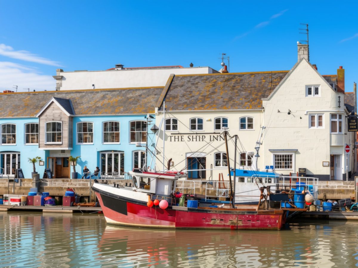 The Ship Inn overlooking Weymouth Harbour with a boat moored on a sunny day in Dorset.