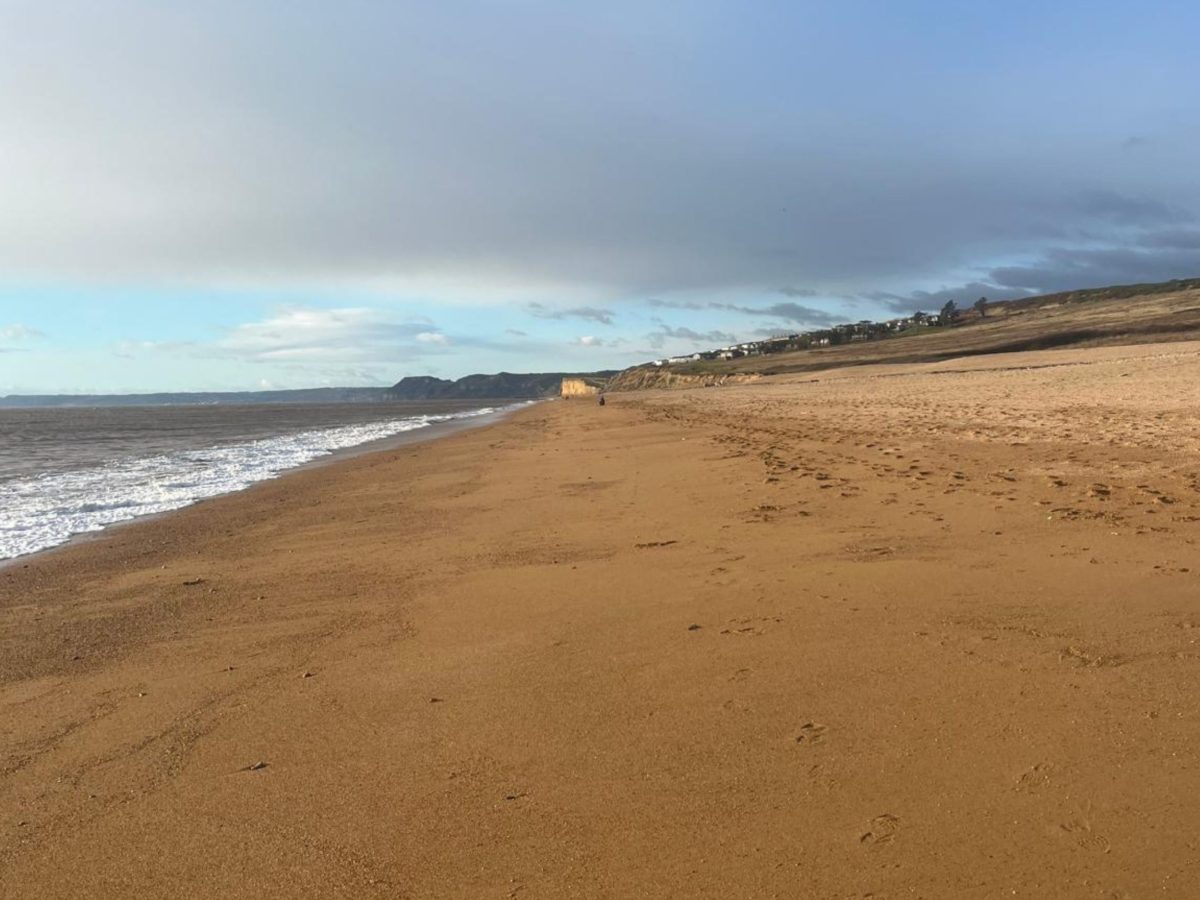 Wide empty sandy beach at Cogden Beach, Dorset, under dramatic skies
