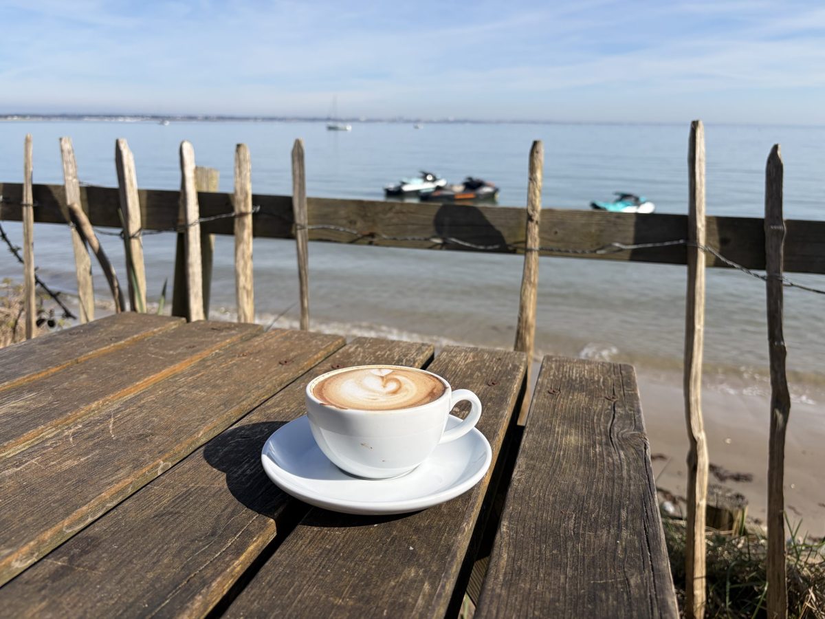 Cup of coffee resting on a table with a sea view at Joe's Cafe, South Beach, Studland, Dorset