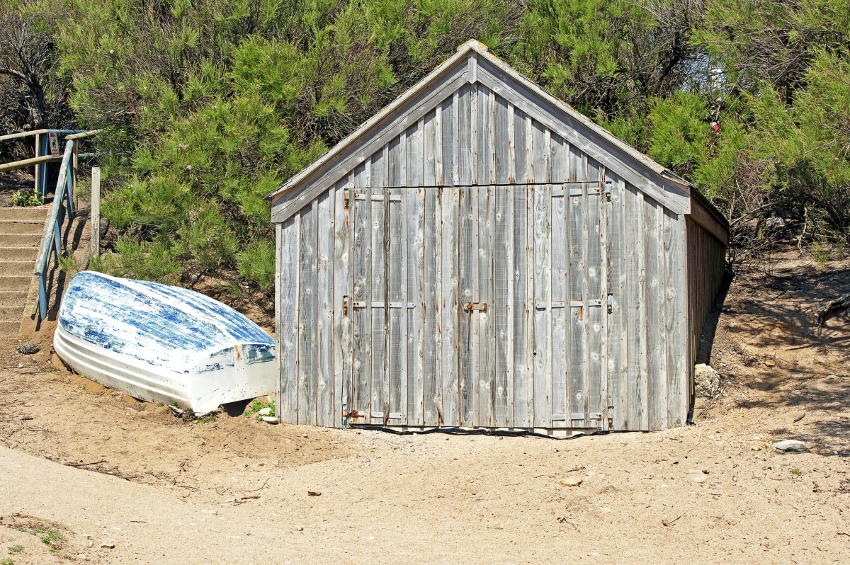 Old wooden shack and mall fishing boat on Hive Beach, Burton Bradstock, Dorset