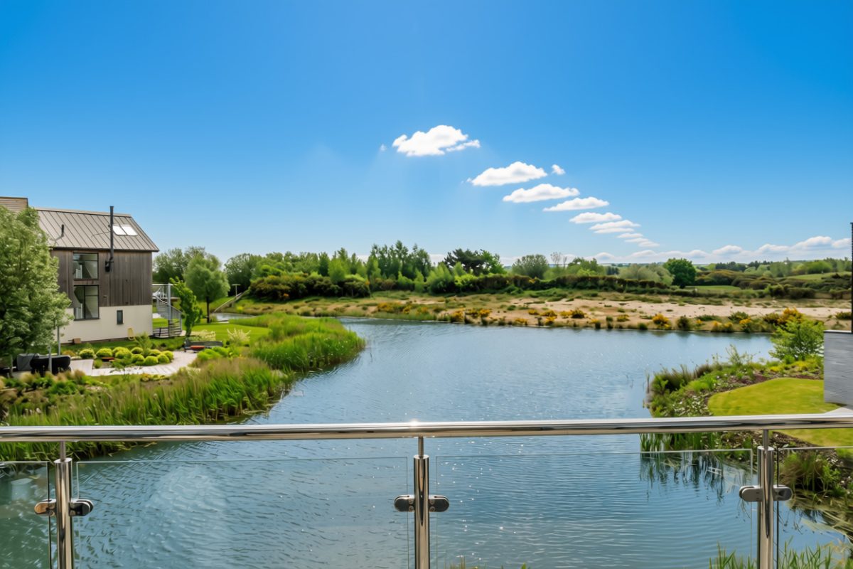 View of a lake from a property balcony at Silverlake Estate, Dorset, on a bright sunny day. 