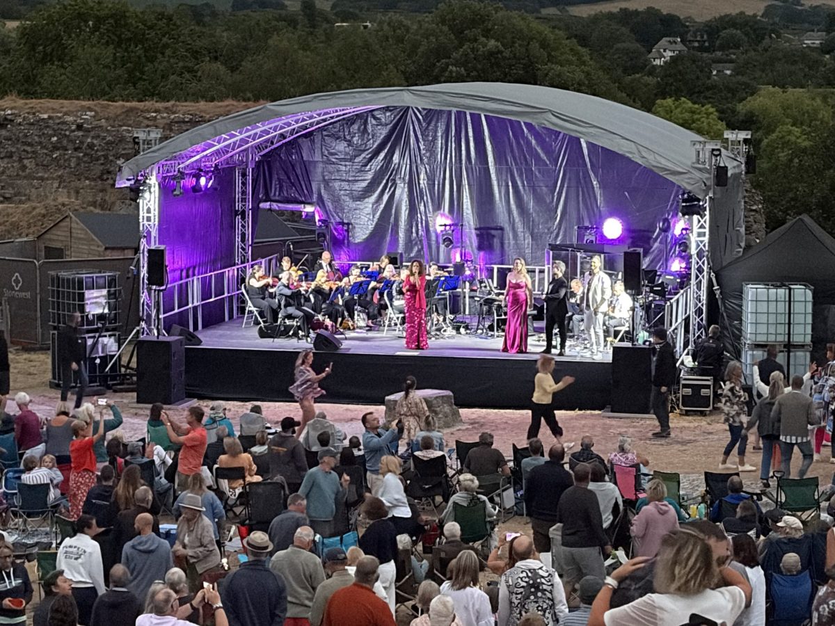 View of concert stage, performers and audience in the ground of Corfe Castle