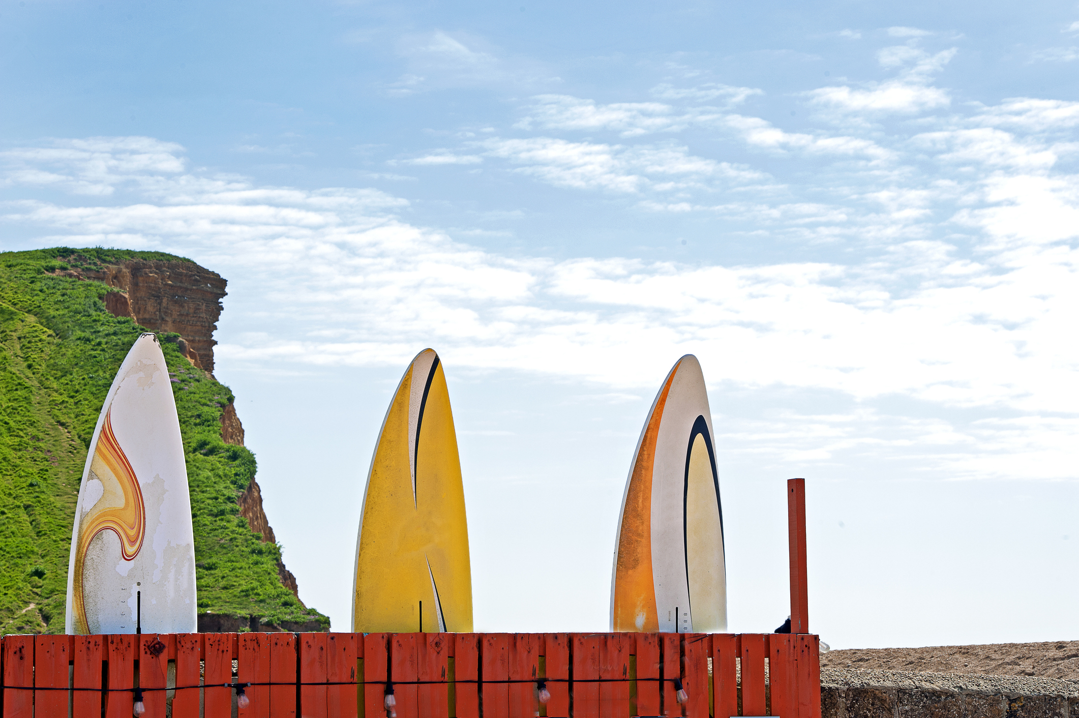 Paddleboards on West Bay beach with the Jurassic Coast cliffs rising behind in Dorset.