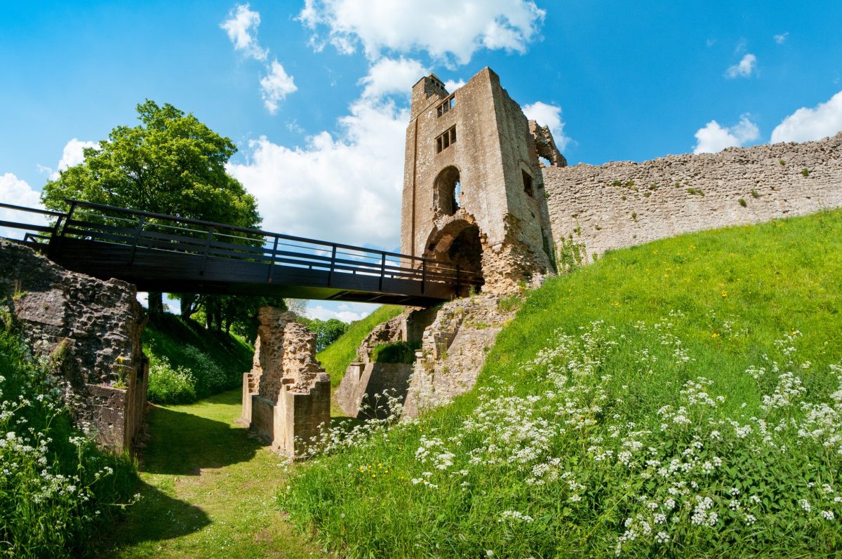 View from below of bridge entrance to Sherborne Old Castle beneath blue skies.