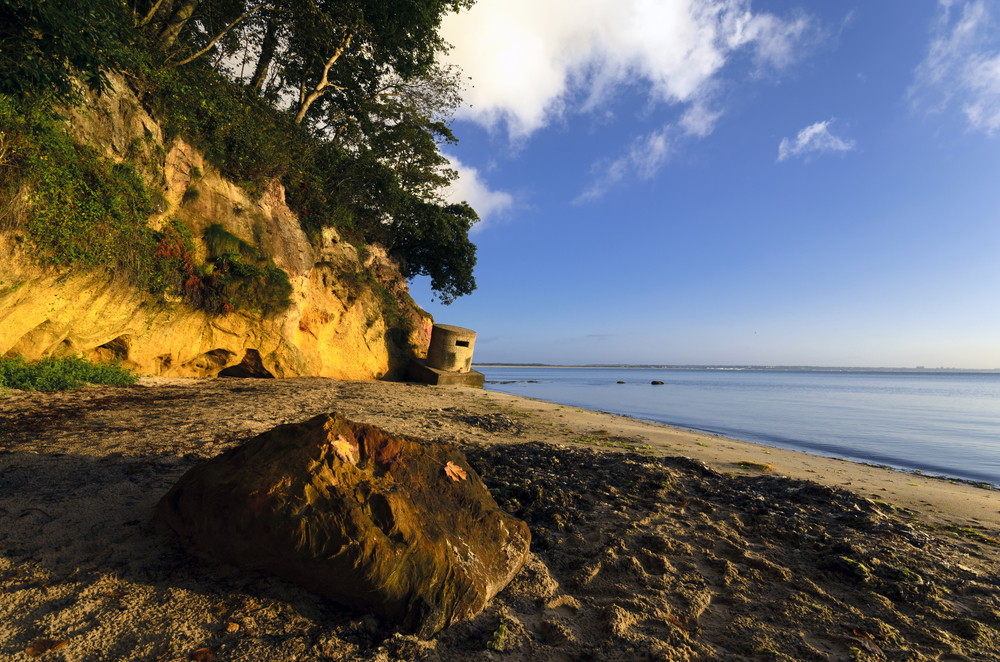 South Beach in Studland as sun hits the cliffs with a Second World War pillbox overlooking the shoreline.