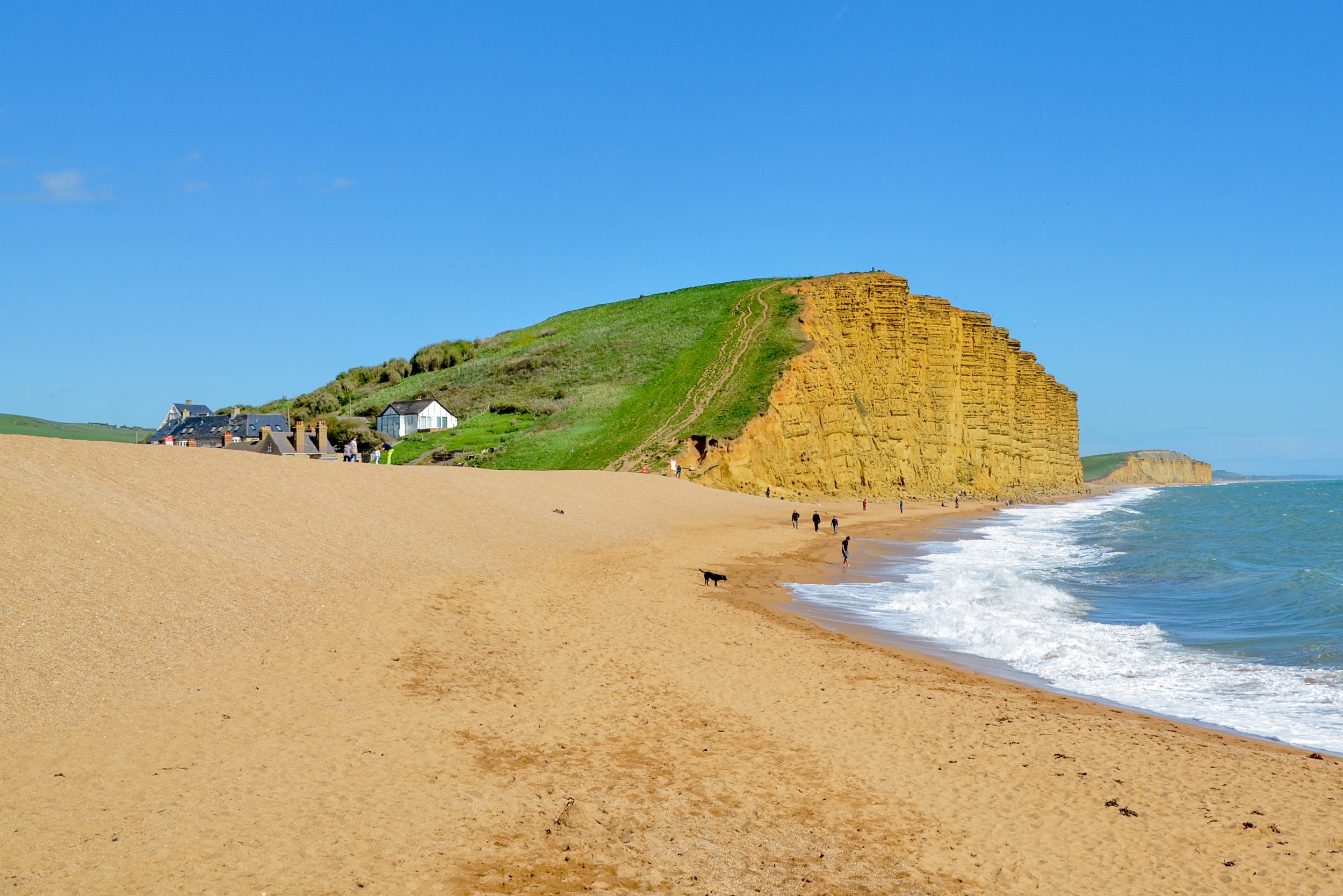 West Bay's golden cliffs, sandy beach and Jurassic Coast coastline under a blue Dorset sky.