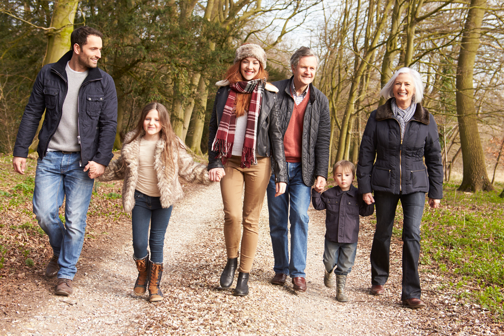 Multi-generational family with children walking together along a woodland track