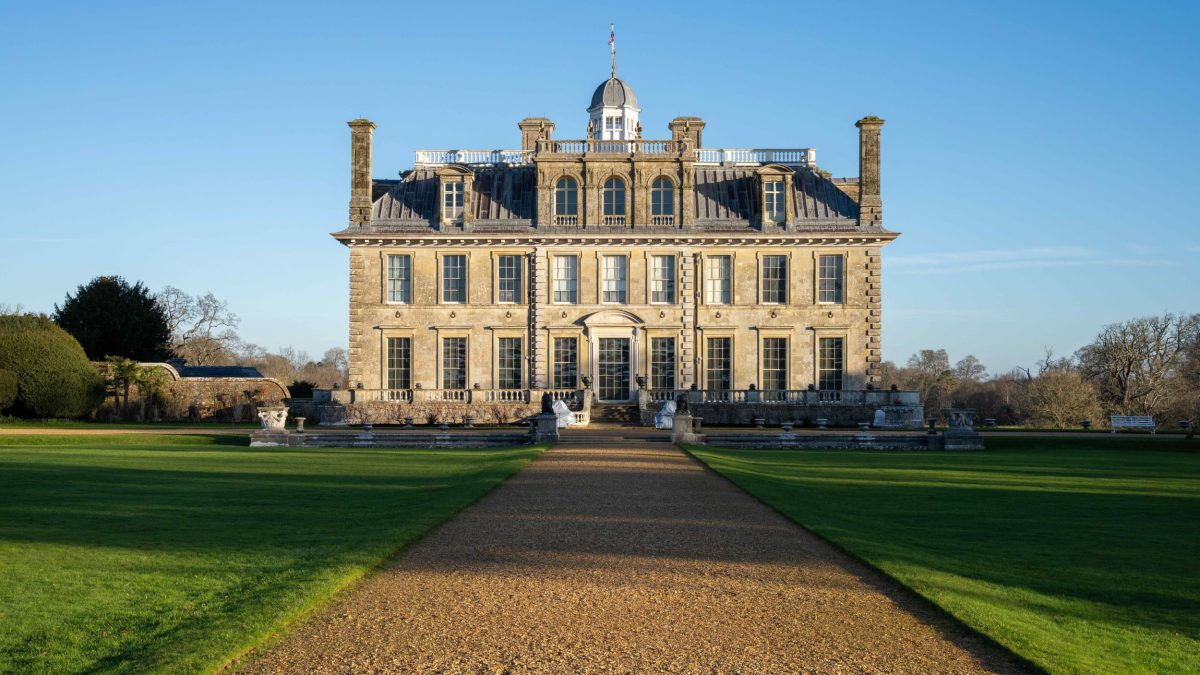 Front view of Kingston Lacy house with green lawns under a blue sky