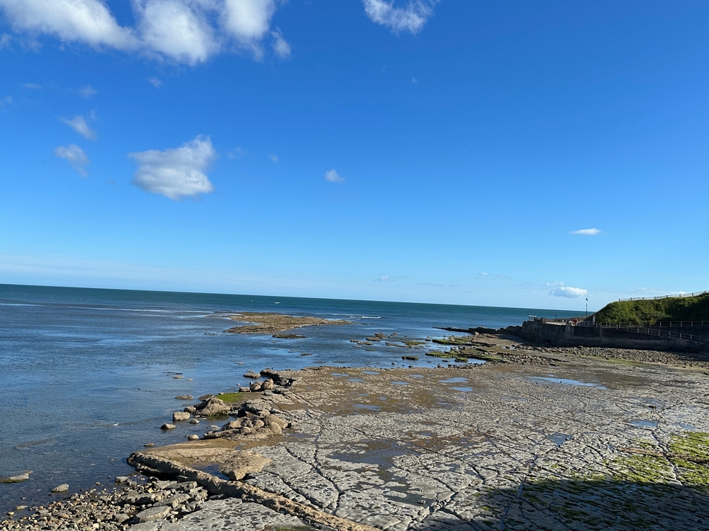 Rocky shoreline at Lyme Regis with the sea and blue sky
