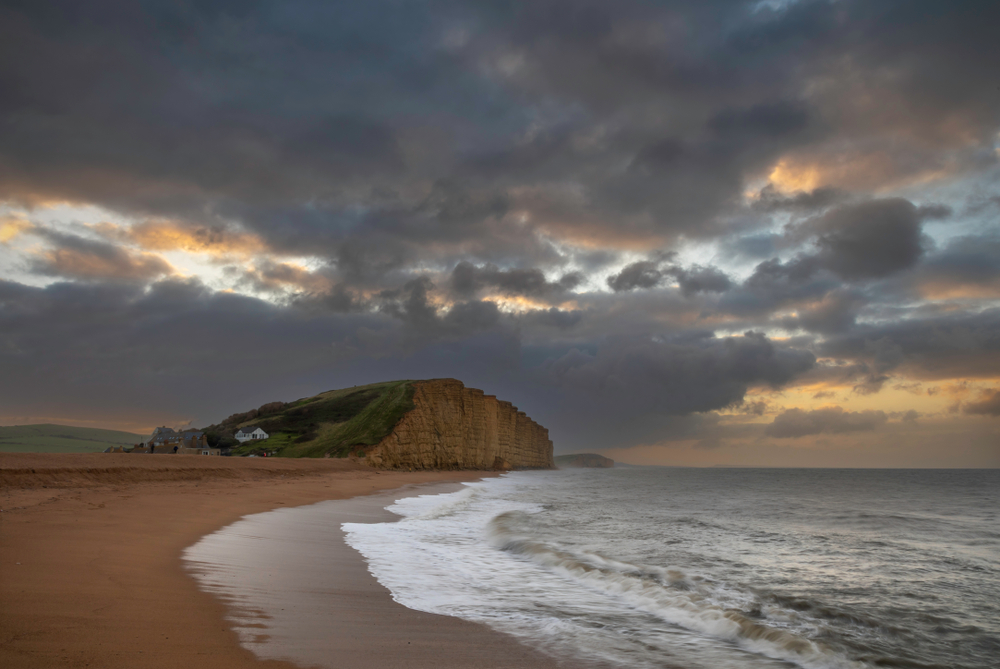 Golden cliffs on the West Dorset coast beneath a dramatic grey autumn sky