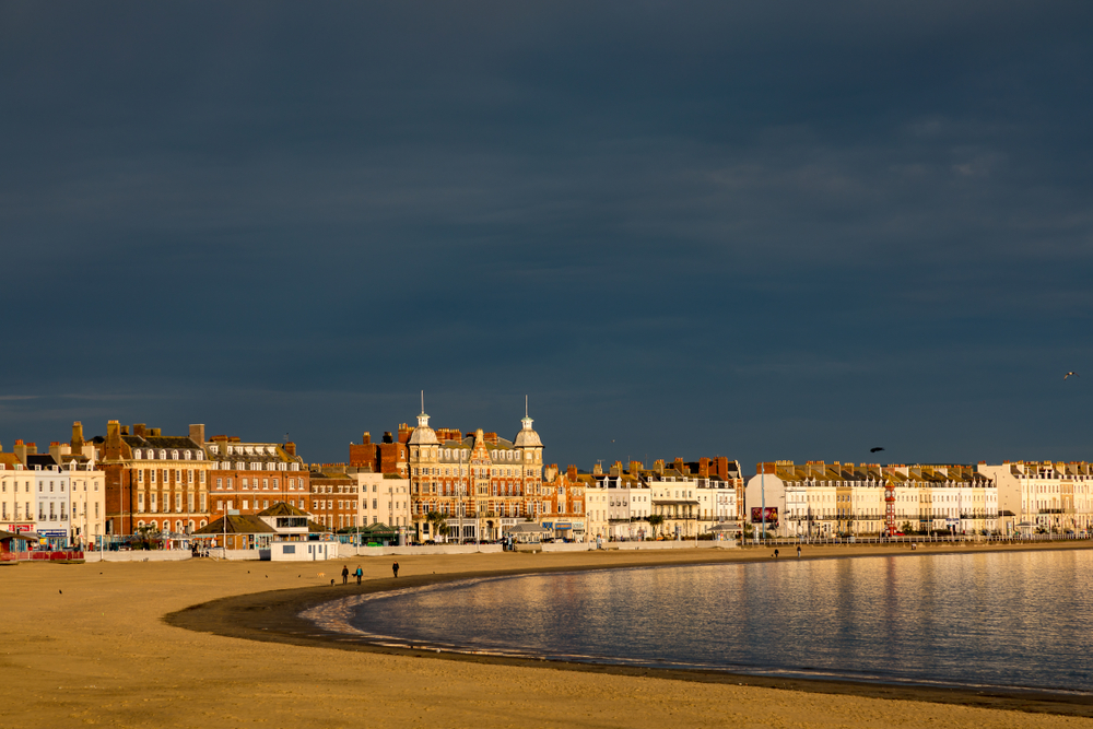 Dark storm clouds gathering over Weymouth Beach and the buildings along the Esplanade in Dorset.